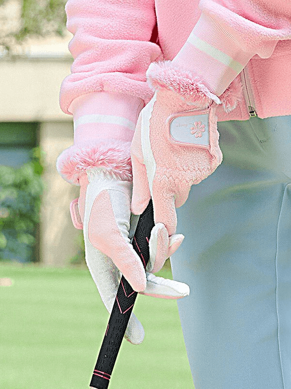Woman wearing stylish pink anti-slip warm gloves for training with a snug fit and fleece finish, holding a golf club.